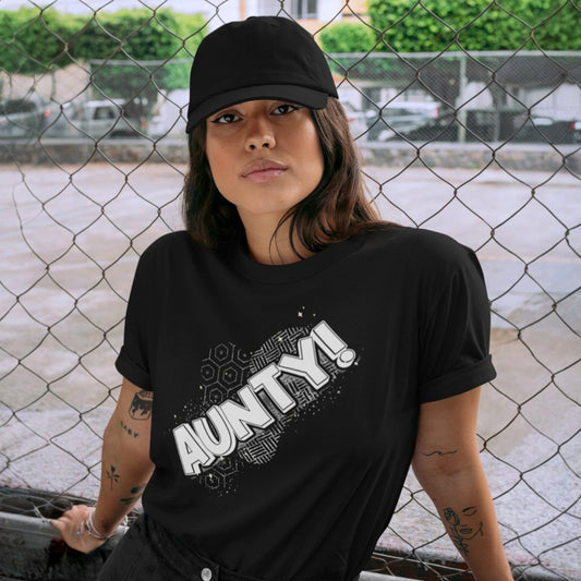 Person wearing a black t-shirt with 'AUNTY!' text, standing in front of a chain-link fence.