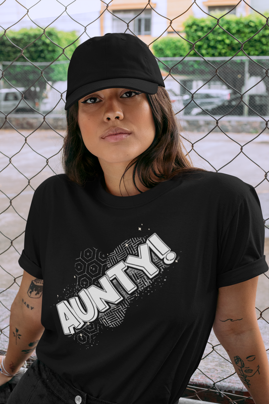 Person wearing a black t-shirt with 'AUNTY!' text, standing in front of a chain-link fence.