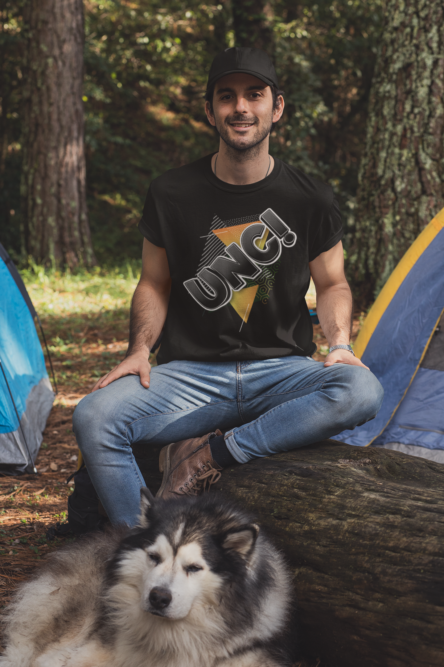 Man sitting with a dog in front of a tent in a forest