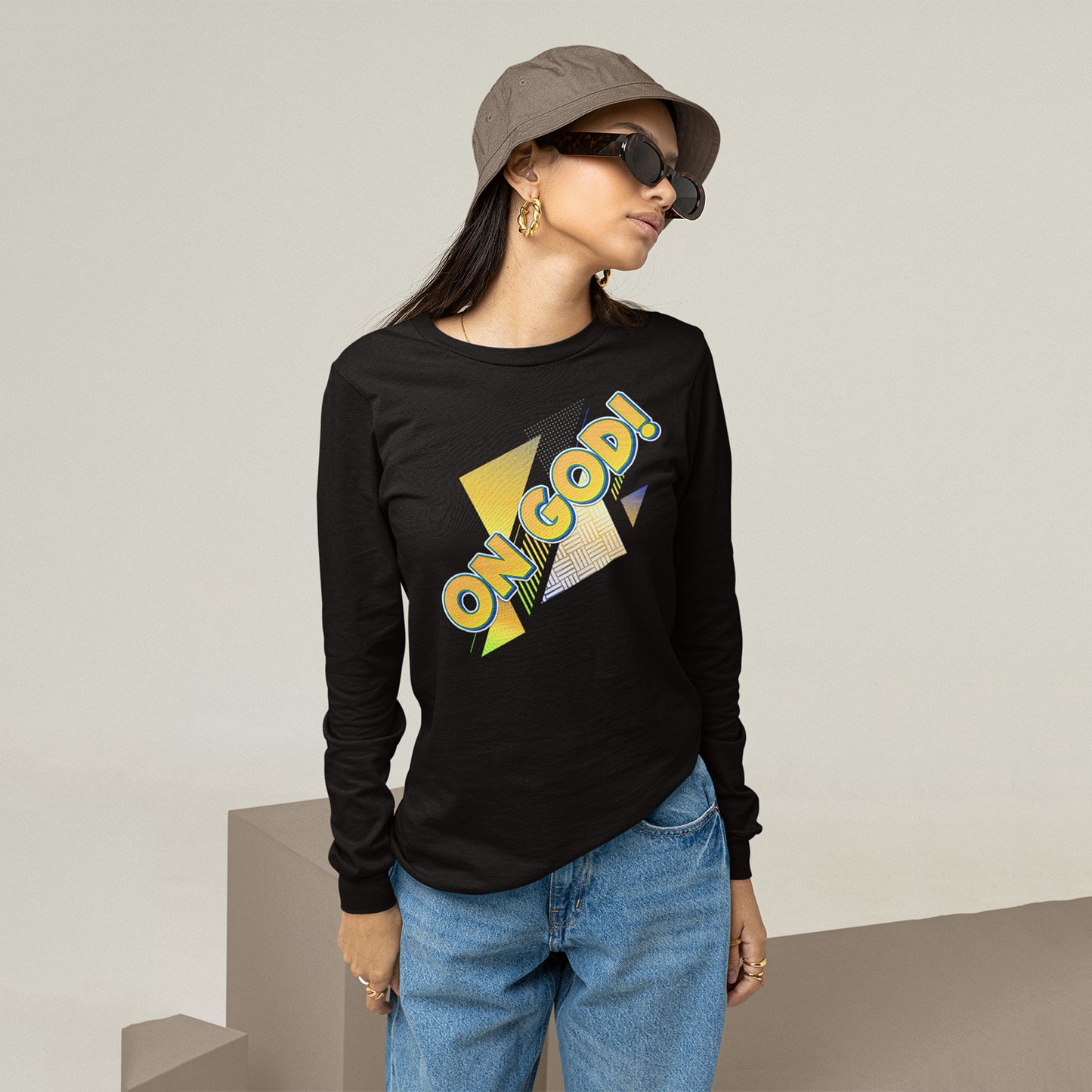 Person wearing a black long-sleeve shirt with colorful text, blue jeans, and a cap.