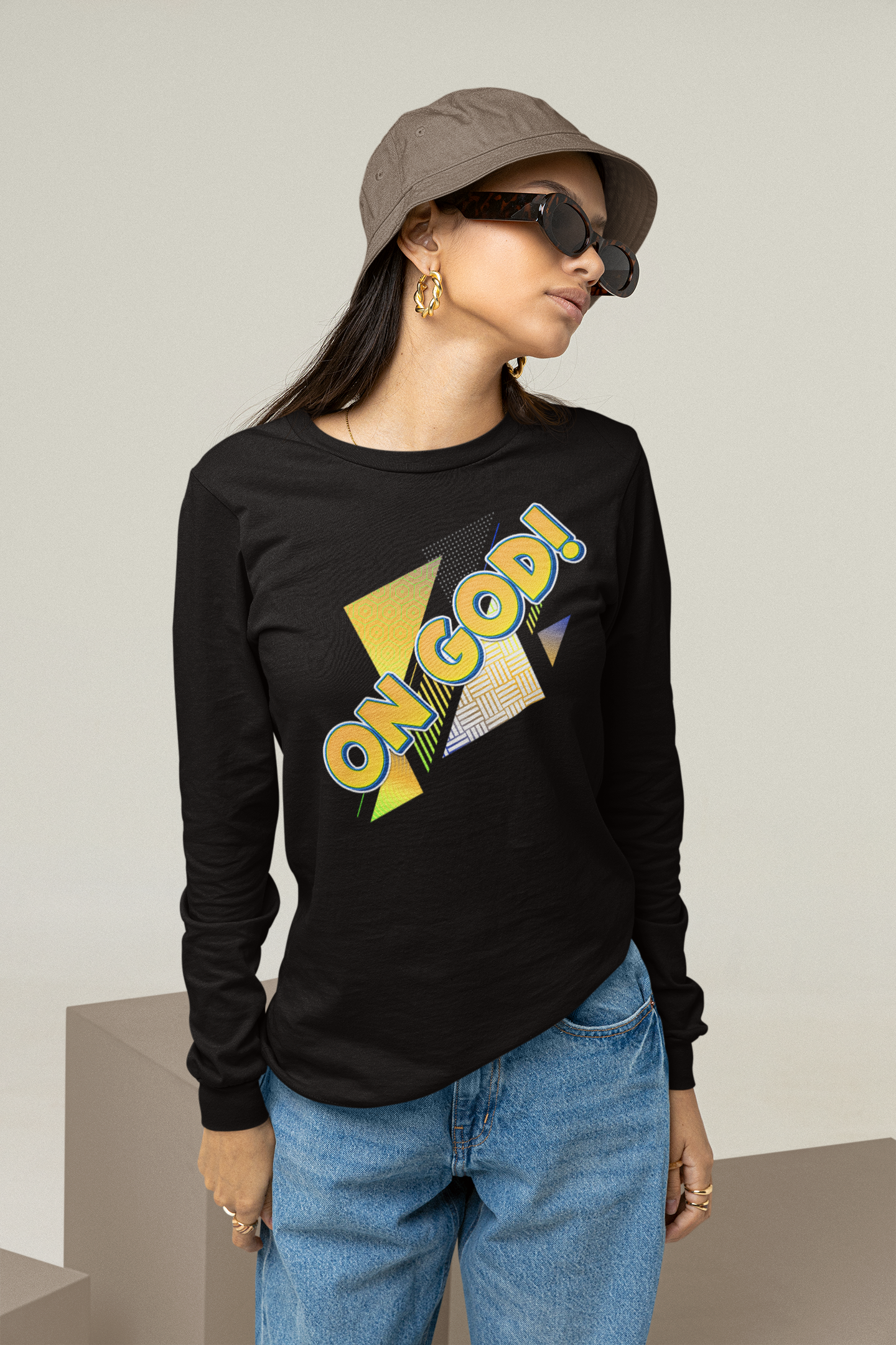 Person wearing a black long-sleeve shirt with colorful text, blue jeans, and a cap.